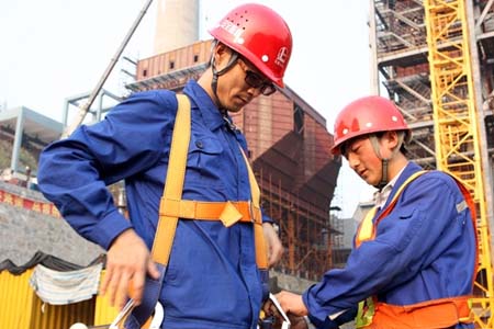 進入高空作業前,同事正在幫他穿戴高空安全帶